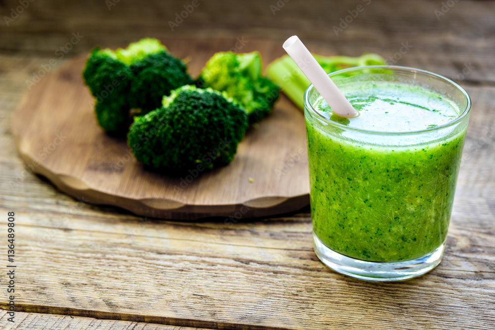 Green vegetable smoothie in glass at wooden background