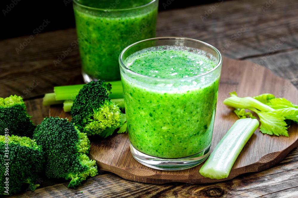 Green vegetable smoothie in glass at wooden background