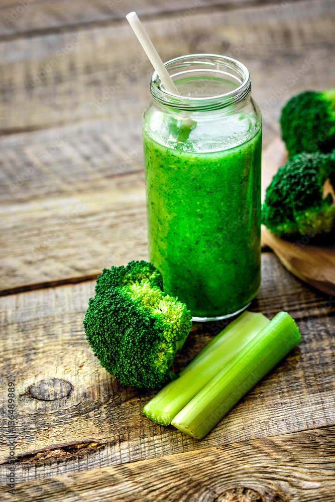 Green vegetable smoothie in glass at wooden background