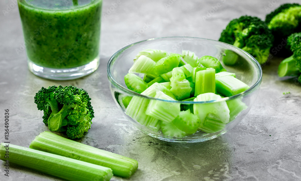 Green vegetable smoothie in glass at gray background