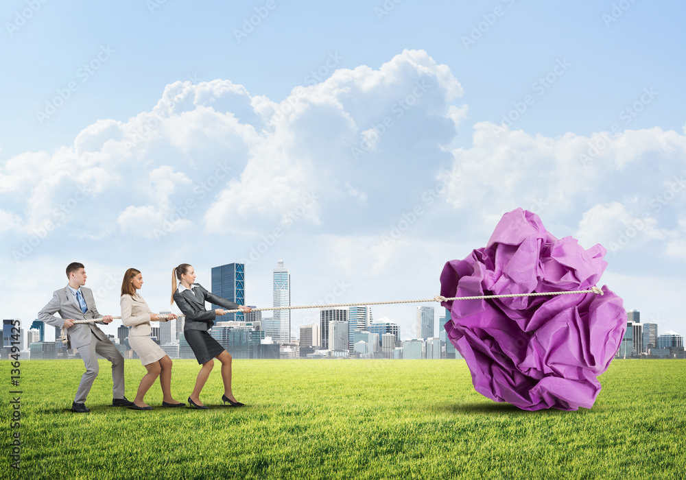 Young business people outdoors and huge paper ball as symbol of creativity