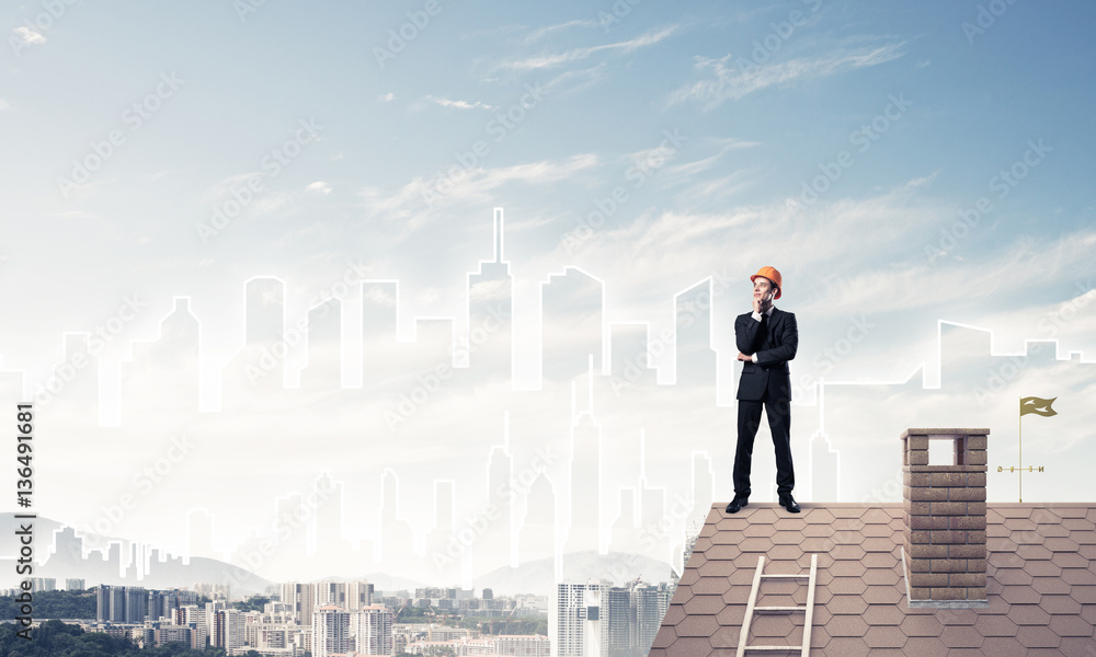 Engineer man standing on roof and looking away. Mixed media