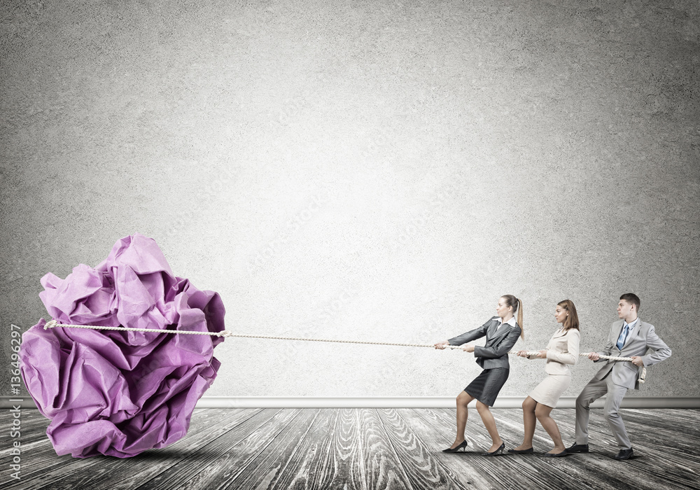 Young business people and huge paper ball as symbol of creativity