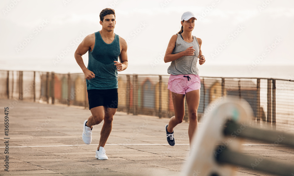 Fitness couple jogging on the sea side promenade