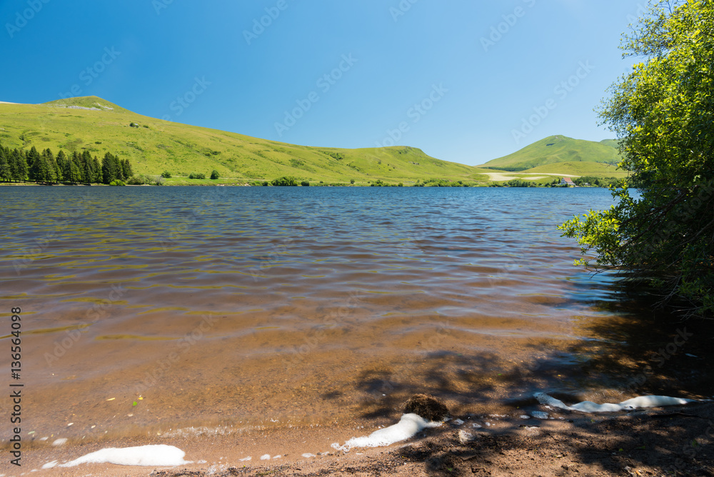 Vue sur le lac de Guery en Auvergne. Montagnes et volcans en arrière-plan. Ciel bleu