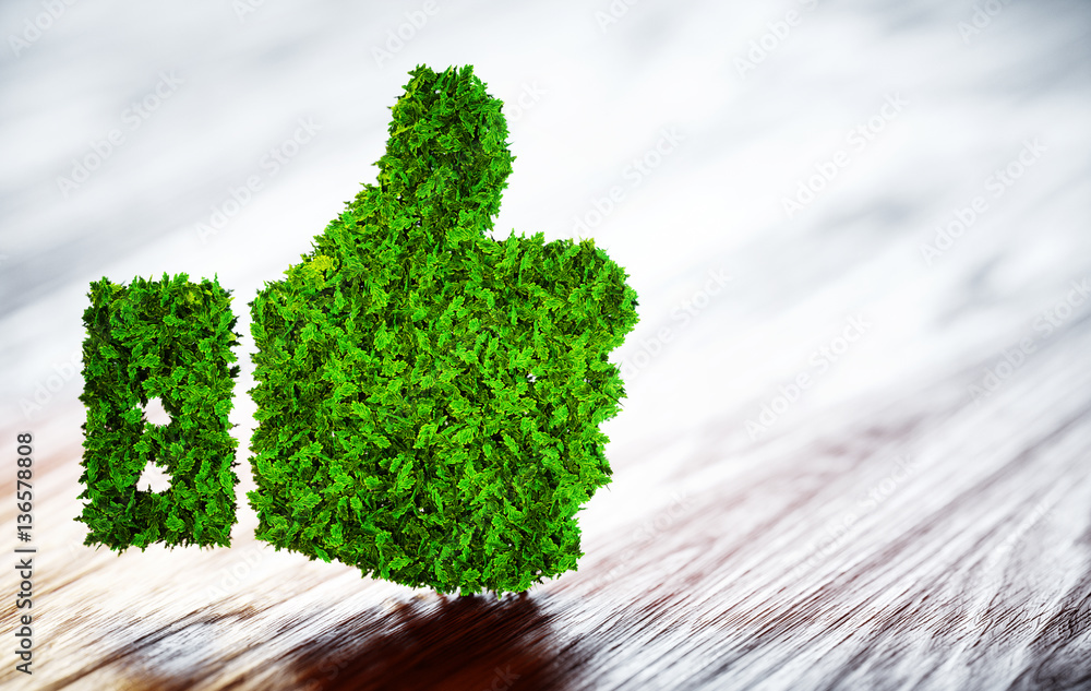 Green thumbs up sign on blurred wooden background.