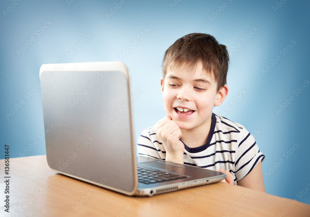 seven years old child in glasses sitting with a laptop at table