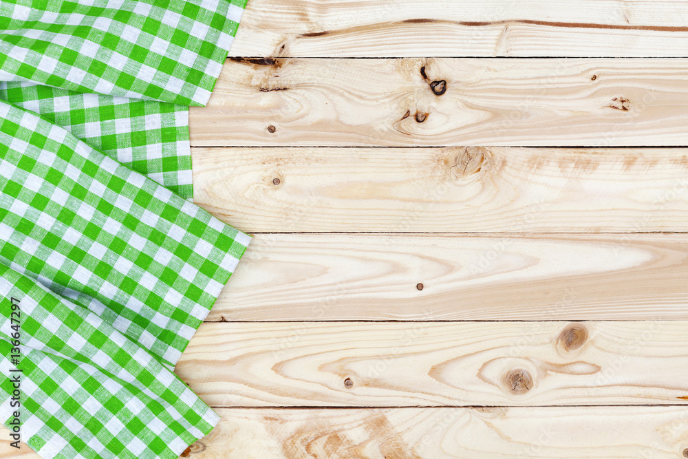 Green checkered tablecloth on wooden table, top view