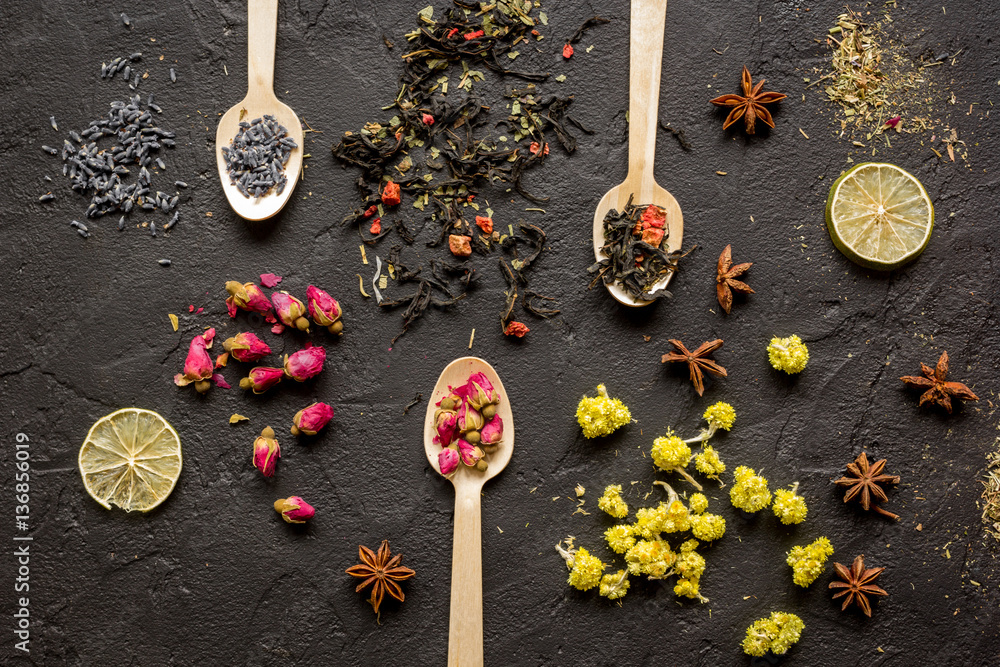 Herbs and flowers on spoons black background top view