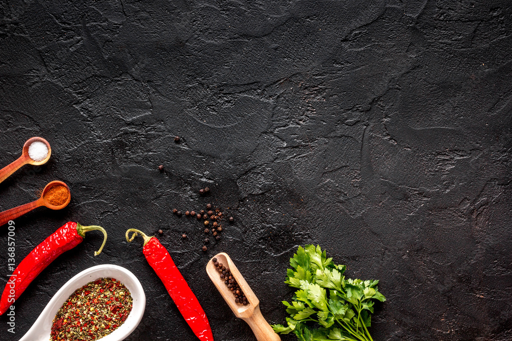 spices in wooden spoon on dark background top view