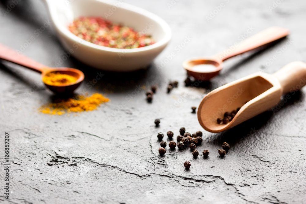 spices in wooden spoon on dark background