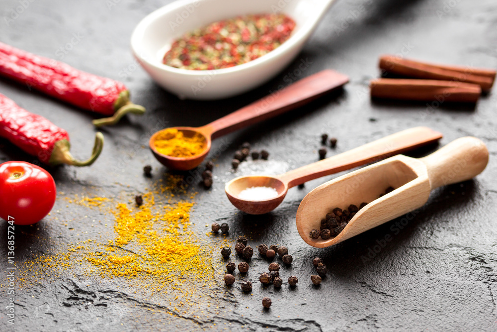 spices in wooden spoon on dark background