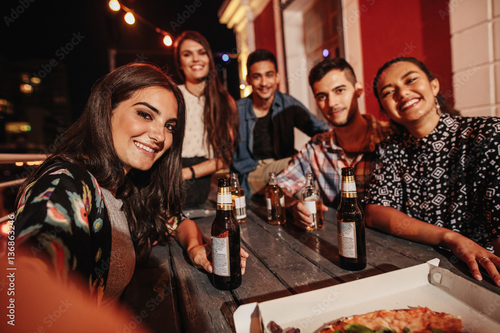 Woman taking selfie with friends at rooftop party