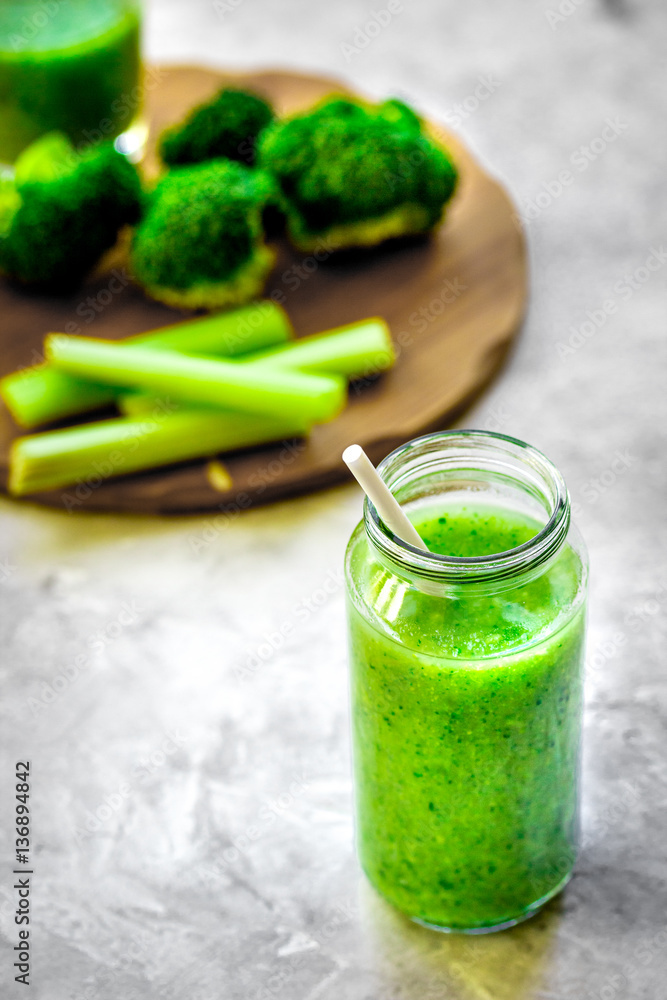 Green vegetable smoothie in glass at gray background