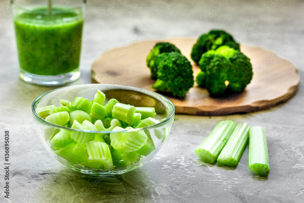 Green vegetable smoothie in glass at gray background