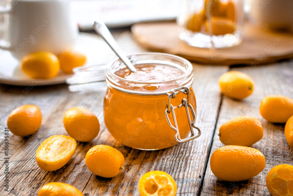 kumquat on plate and jam in jar at wooden table