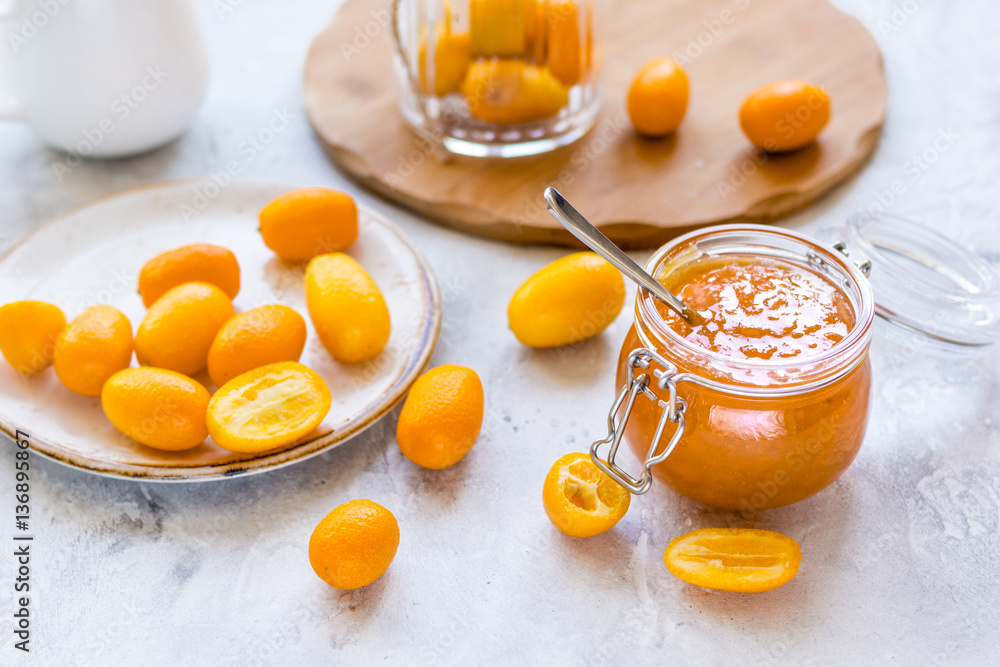 kumquat on plate and jam in jar at gray background