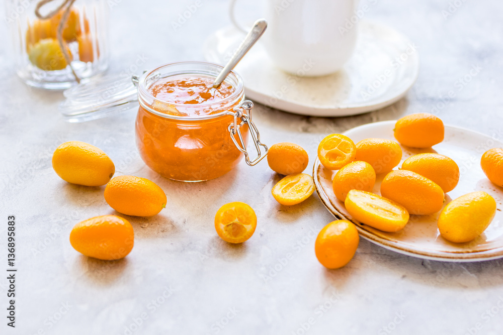 kumquat on plate and jam in jar at gray background