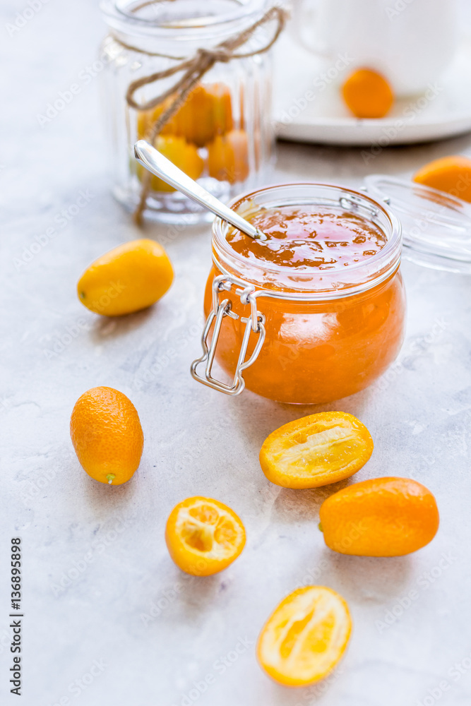 kumquat on plate and jam in jar at gray background