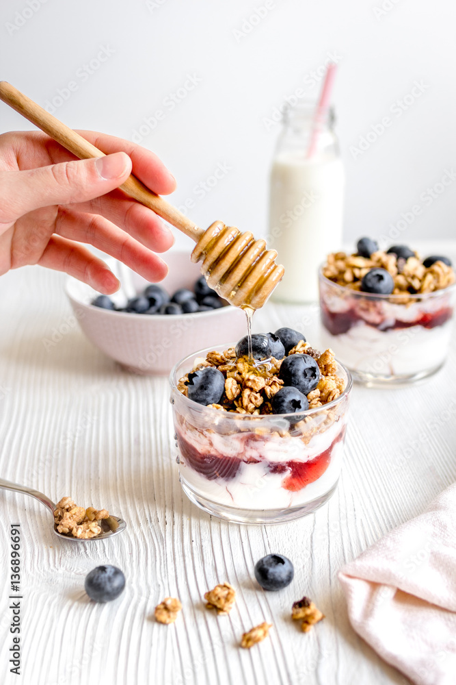 Cooking breakfast with granola and berries on white kitchen background