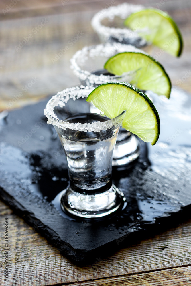 Bar set with shots, fresh lime and salt on wooden background