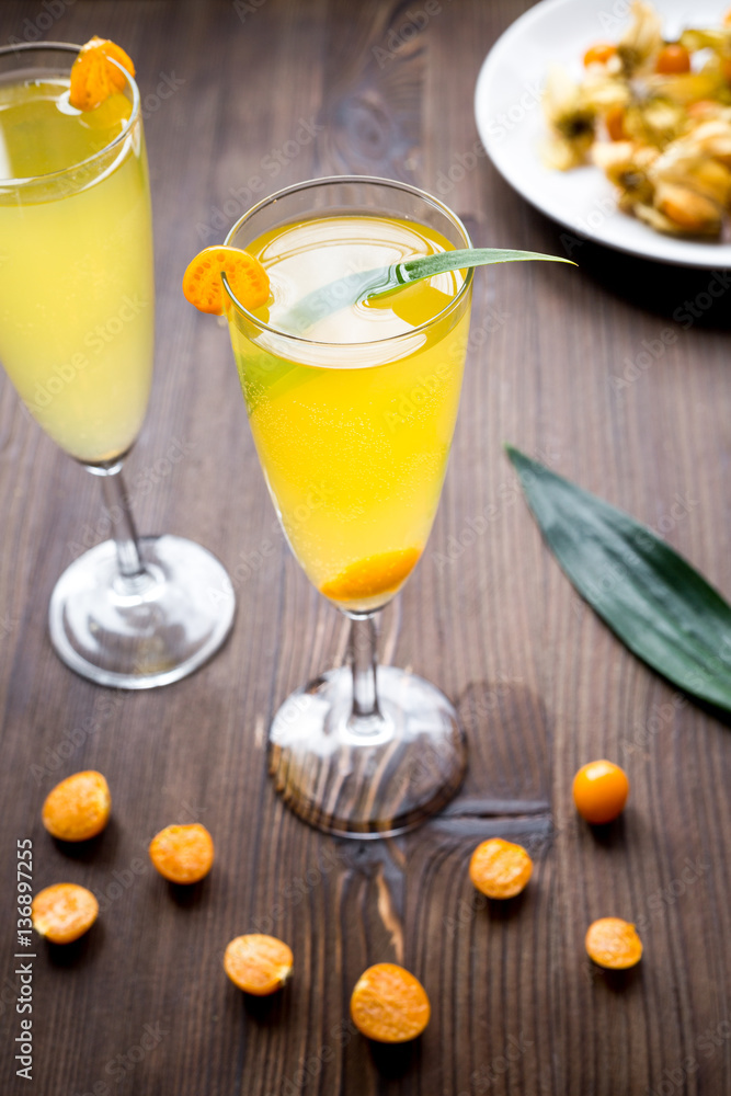 cocktail with physalis in glass on wooden background