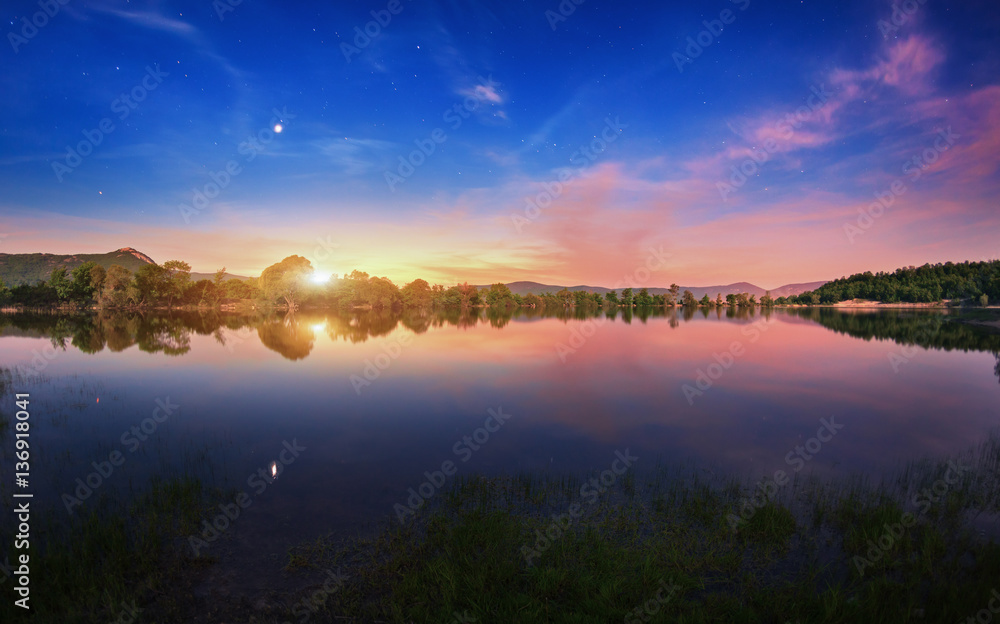 Mountain lake with moonrise at night. Night landscape with river, trees, hills, moon, stars and colo