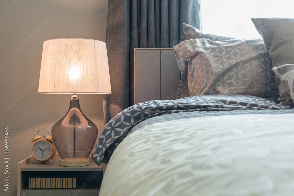 classic lamp style with alarm clock on table side in cozy bedroo