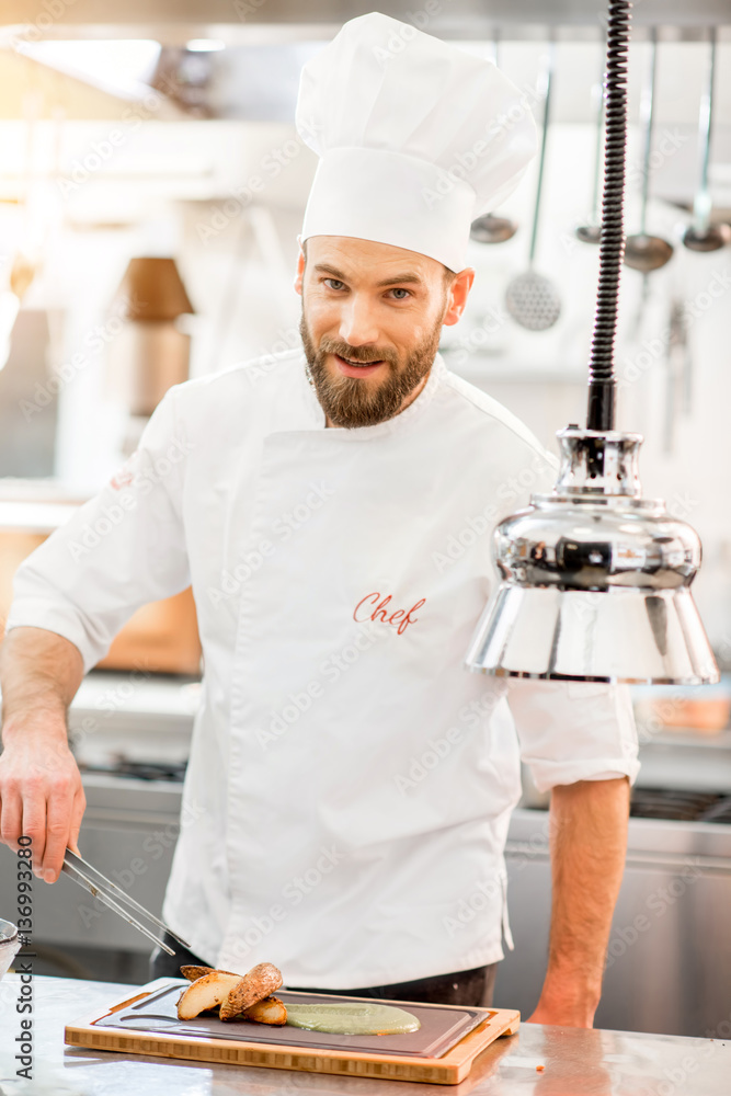 Chef cook in uniform finishing delicious meal at the restaurant kitchen