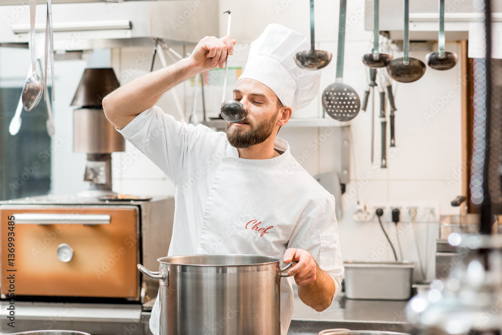 Chef cook tasting food with big scoop at the restaurant kitchen