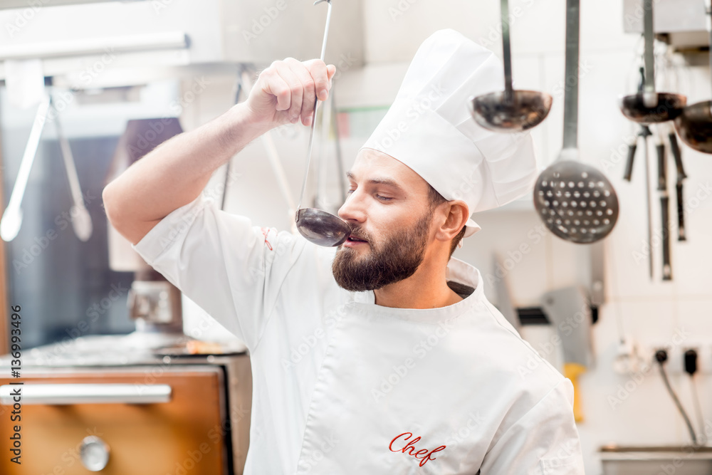 Chef cook tasting food with big scoop at the restaurant kitchen