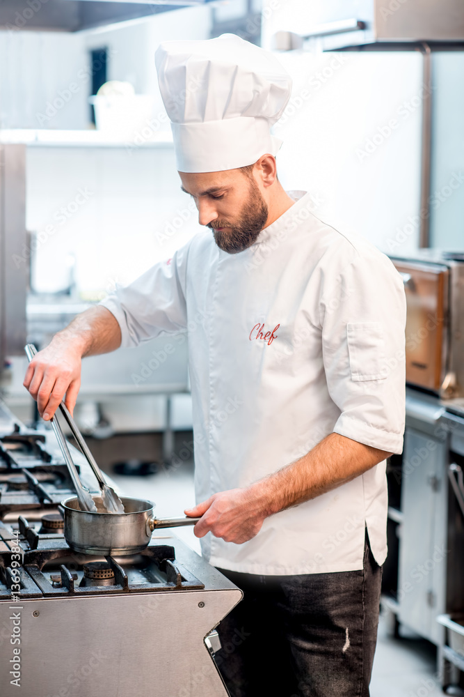 Portrait of chef cook in uniform with knifes at the restaurant kitchen