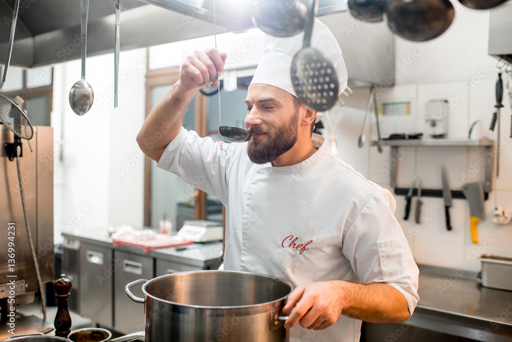 Chef cook tasting food with big scoop at the restaurant kitchen