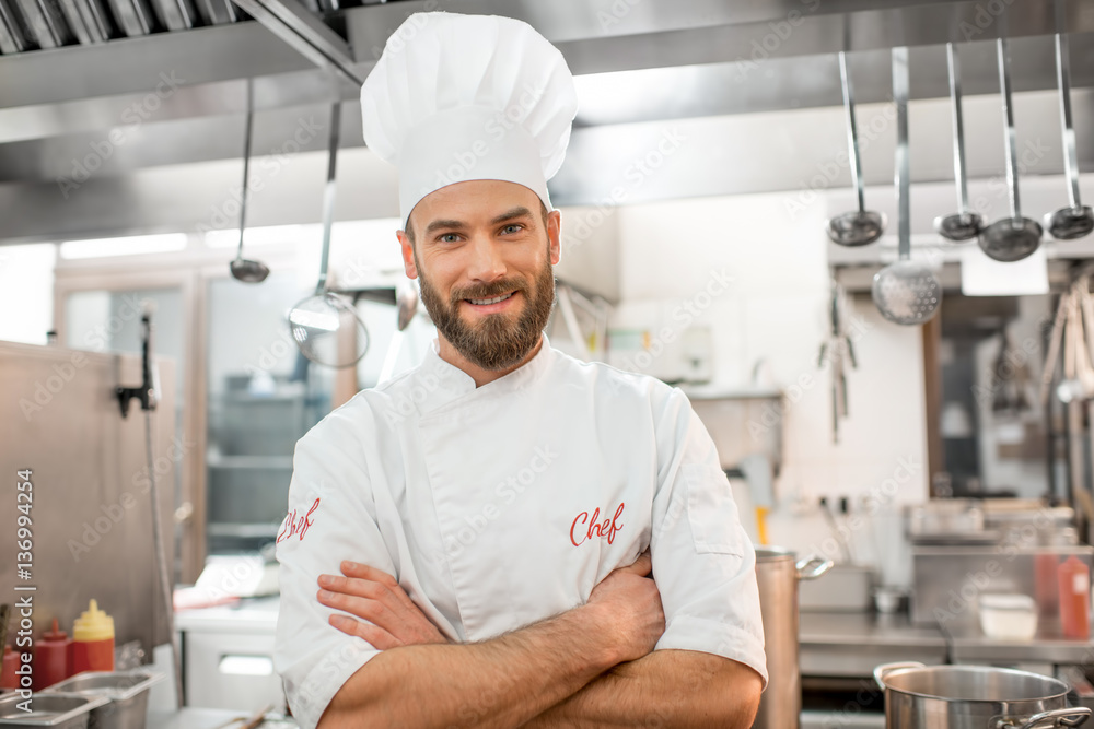 Portrait of a handsome chef cook in uniform at the restaurant kitchen