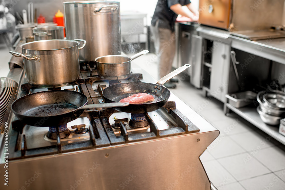 Chef frying meat steak on the gas stove at the kitchen