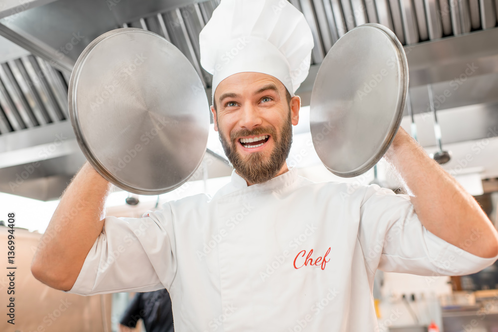 Crazy chef cook holding pan covers at the restaurant kitchen