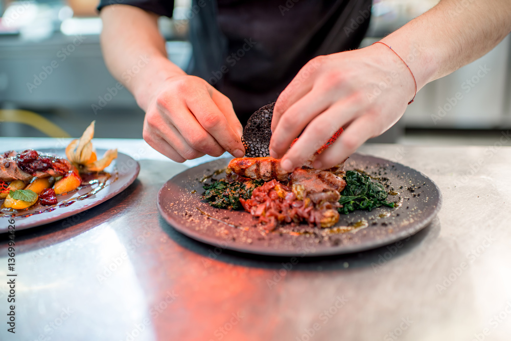 Finishing delicious restaurant dish with meat on the restaurant kitchen