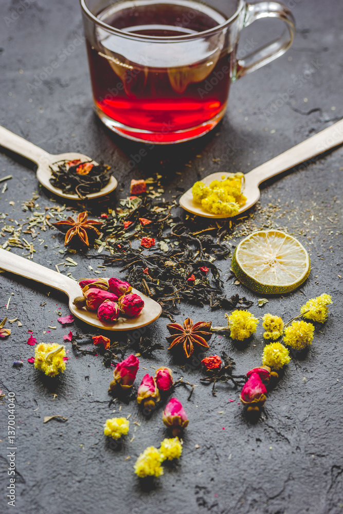 Teacup and herbs on dark stone background