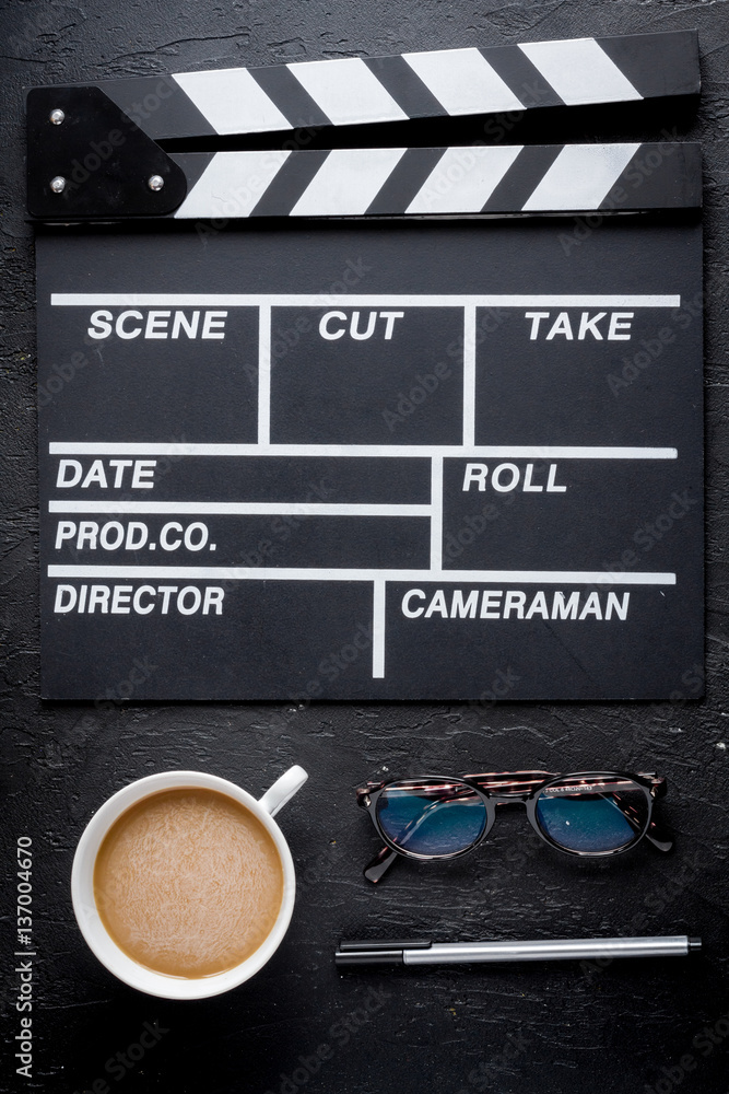 Screenwriter desktop with movie clapper board dark background top view