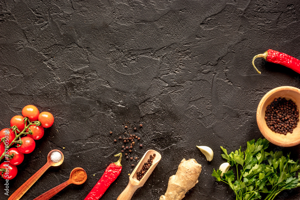 spices in wooden spoon on dark background top view