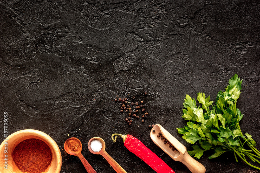 spices in wooden spoon on dark background top view