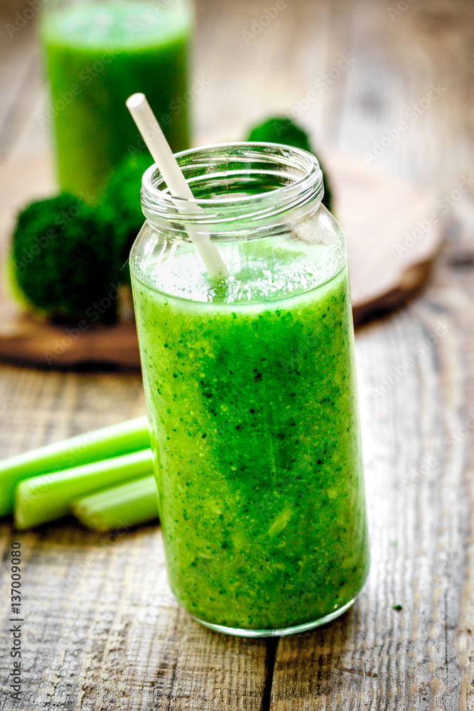 Green vegetable smoothie in glass at wooden background