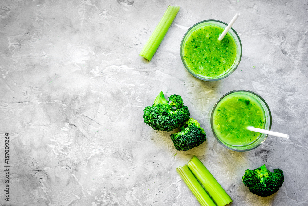 Green vegetable smoothie in glass at gray background top view