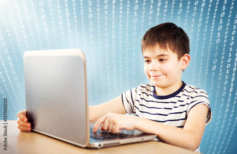 seven years old child sitting with a laptop at table and typing