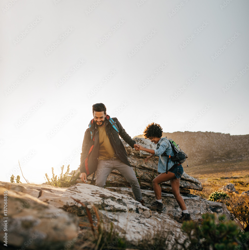 Young couple hiking help each other in mountains