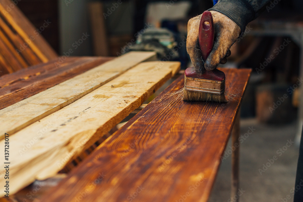 Varnishing a wooden plank using paintbrush