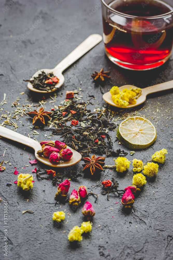 Teacup and herbs on dark stone background