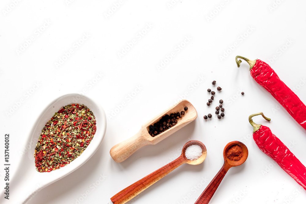 spices in wooden spoon on white background top view