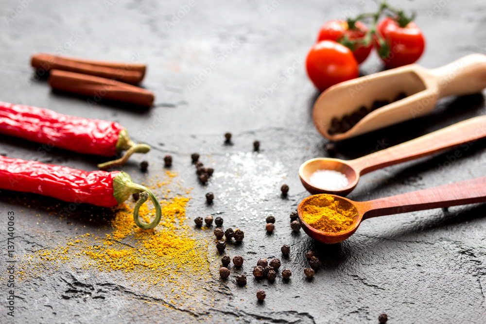 spices in wooden spoon on dark background