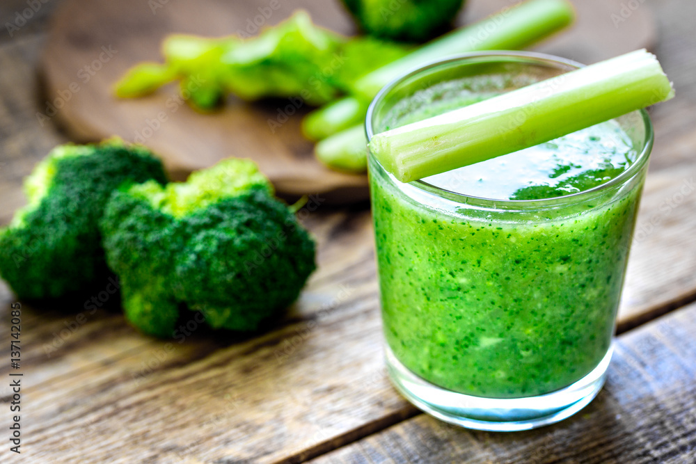 Green vegetable smoothie in glass at wooden background